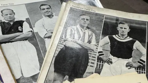 Two magazines lie open, showing pictures of footballers in black and white from the mid-20th century.