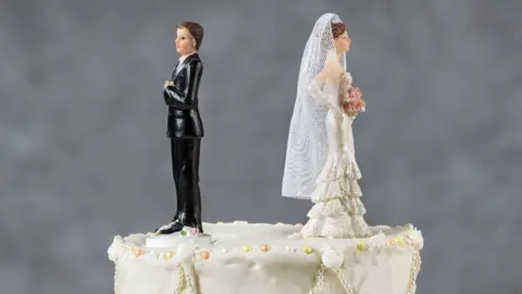 Getty Images bride and groom on cake facing away