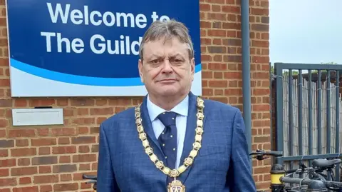 LDRS Duncan pictured smiling slightly and looking into the camera - he's wearing a dark blue suit, a navy tie, and light blue collared shirt. He's got his chairman's chains of office on over the top - it's an ornate gold piece with a pendant that has Shropshire's coat of arms on it.