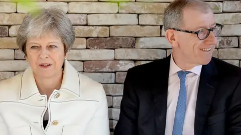 AFP via Getty Images MAY 21: British Prime Minister Theresa May (L) and husband Philip May (R) attend the Chelsea Flower Show 2018 on May 21, 2018 in London. She is wearing a white jacket and he is wearing a dark suit