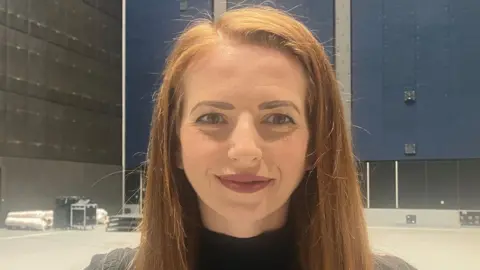 Katy Egan-Daynes smiles for the camera while stood in a production space at the Aviva Studios building