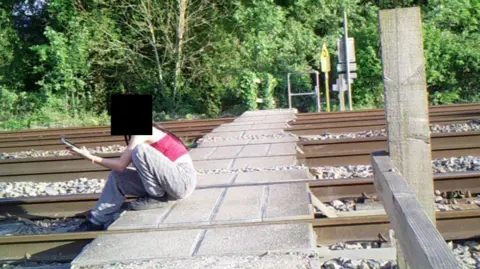 A young girl sat on the crossing taking a selfie
