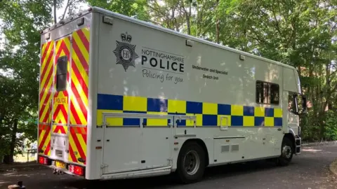 Tom Jackson/BBC A lorry from the police underwater search team at the lake near Cambridge