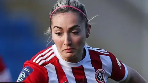 Getty Images A close up of Maddy Cusack's face, she is playing in a match and wears a Sheffield United shirt