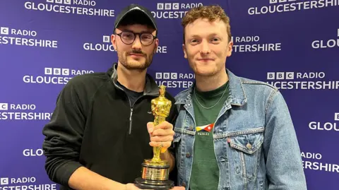 Tom and Ross holding an Oscar award