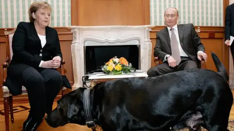 AFP Russian President Vladimir Putin (R) and German Chancellor Angela Merkel are watched by Putin's dog Koni as they address journalists after their working meeting at the Bocharov Ruchei residence in Sochi, 21 January 2007.