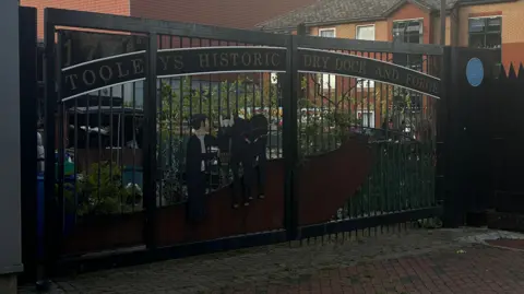 The front gate of Tooley's boatyard - which has a decorative artwork of a man and a donkey on.