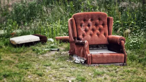 SEAN GLADWELL/GETTY IMAGES An armchair and mattress abandoned in a field