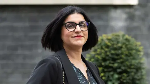 Rasid Necati Aslim/Anadolu via Getty Images Home Secretary Shabana Mahmood, in a black suit jacket and black-rimmed glasses, arrives at Downing Street to attend the weekly cabinet meeting in London