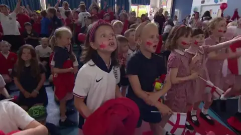 A group of school children watching the England v Mexico game