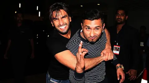 Getty Images Ranveer Singh (L) wears a black shirt, blue jeans, and Singh honey (PB