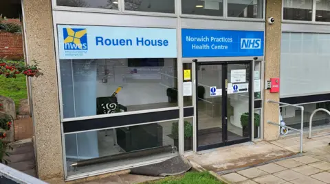 The entrance to Norwich's NHS walk-in centre. There is an automatic door and a large window to the left.