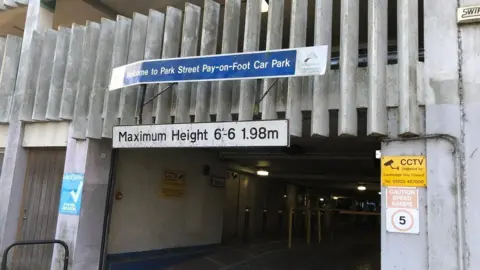 Entrance to the Park Street car park. The photo, taken in 2020, shows the grey concrete building with various saftey signs for speed and CCTV. 