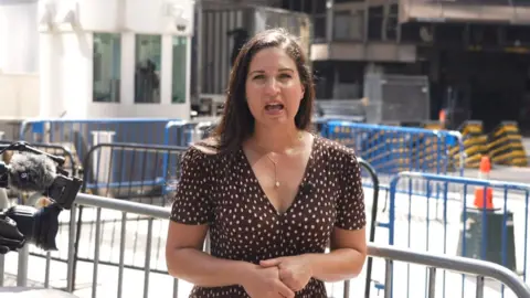 Nada Tawfik stands on a sidewalk outside Madison Square Garden, wearing a brown dress with white dots.