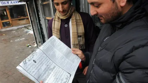 Getty Images Men reading a newspaper in Srinagar