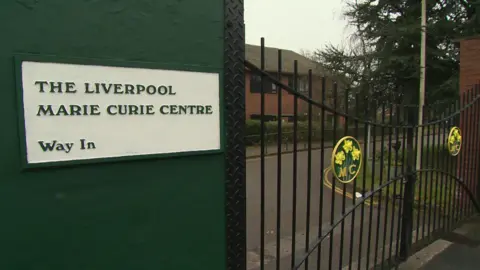 The exterior of the hospice's closed gates with its name and "way in" sign next to them