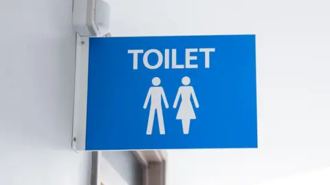 A blue male and female toilet sign mounted on a white wall.