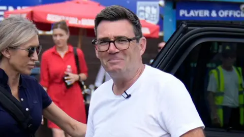PA Media Andy Burnham arrives at Radcliffe Football Club. He is in a close-up, wearing a white t-shirt.
