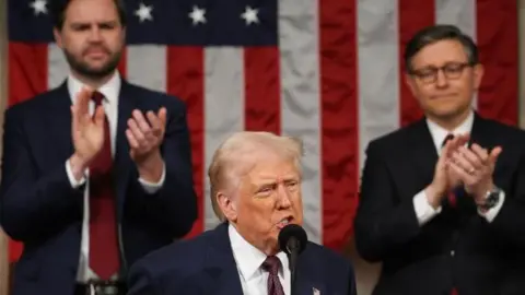 EPA US President Donald Trump, wearing a navy blue suit with a white shirt and maroon tie, addresses the US Congress.