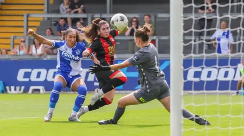 Getty Images Players from Bristol Rovers Women and AFC Bournemouth Women football teams tussle for the ball at the Memorial Stadium in Bristol. The ball is seen flying past the Rovers goalkeeper on its way into the net