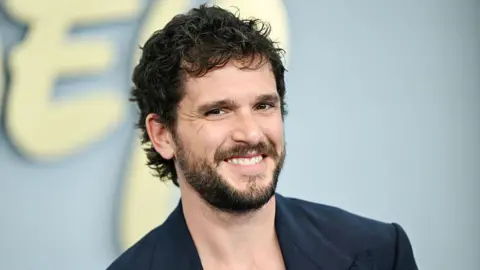 Variety via Getty Images Kit Harrington seen smiling on the red carpet in a blue blazer on the red carpet in New York in May.