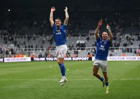 Reuters Sunderland's Chemsdine Talbi and Granit Xhaka celebrate after the match on the pitch at St James in Newcastle. The two are wearing their match kit, a blue top and white shorts, and are both jumping in the air, with their arms up and they are smiling towards the dan which are out of shot.