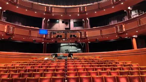 Matt Knight/BBC An empty theatre with several rows of red seats.