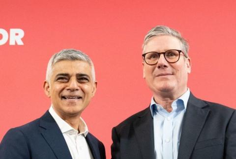 Sadiq Khan and Sir Keir Starmer stand in front of a red background