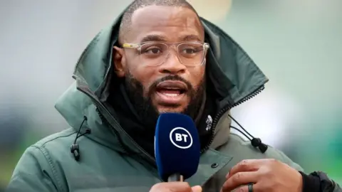 Getty Images Ugo Monye holding a microphone