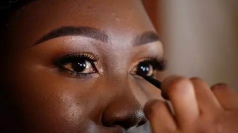 A close shot of a woman having kohl liner applied to her eyes.