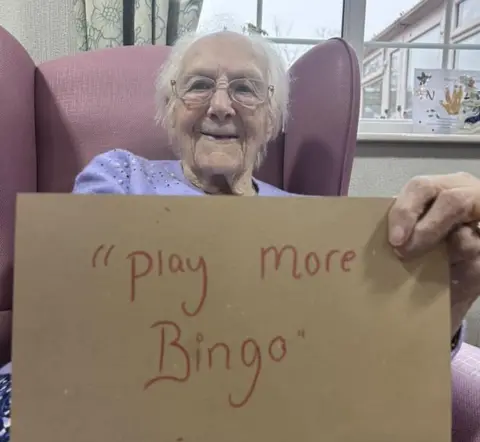 Temple Croft Care Home A resident holds up a sign reading 'Help more people'