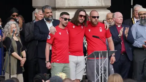 PA Media Ian Coates' sons wearing Nottingham Forest shirts at vigil