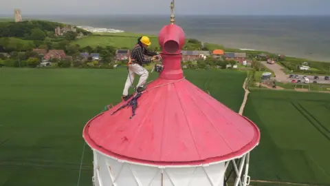 Joe Giddens Man painting Happisburgh Lighthouse