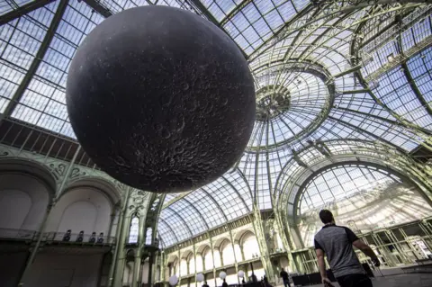 EPA A replica of the moon hangs from the glass ceiling of the Grand Palais ahead of the "Mooon Party" celebrating the 50th anniversary of the moon landing, in Paris, France