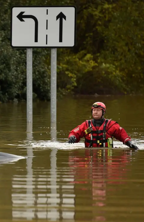 AFP A member of the Fire and Rescue service wades through flood water