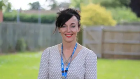 NHFT Woman with very dark hair wearing an NHS lanyard