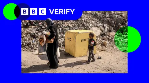 A Palestinian family carried belongings alongside a large yellow block, part of the so-called 'Yellow Line', where Israeli forces are stationed