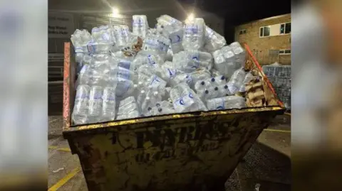 A skip filled with bottles of water. 
