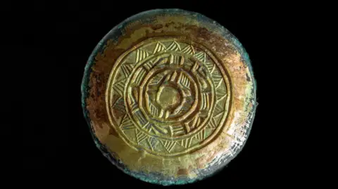 Discover Bucks Museum A saucer-shape gilded Saxon bronze woman's brooch. It decorated with four circular lines with triangular patterns between each circle. 