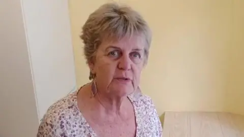 Alison Theaker stood in her utility room looking straight at the camera. She is stood in her kitchen and has an annoyed look on her face. 