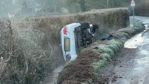 A white car overturned on its side in a river