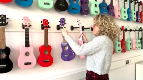 Teacher putting her guitars away.