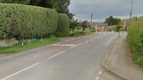 The A4111 going from the bottom left to roughly the top right on the photo. Bushes and trees are prominent on the left of the image.