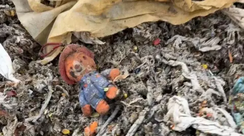 A Paddington bear toy amongst a pile of wet wipes
