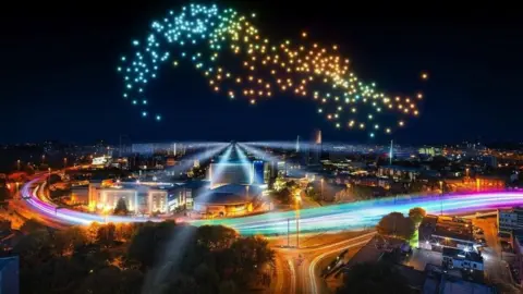 City of Culture A night-time image of Coventry, showing dozens of lights in the sky created by drone. There are also colourful beams of light running along the city's ring road. 
