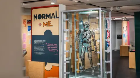 Thackray Medical Museum The inside of a museum showing a case with a metal suit of armour and a sign which reads 'normal and me'.