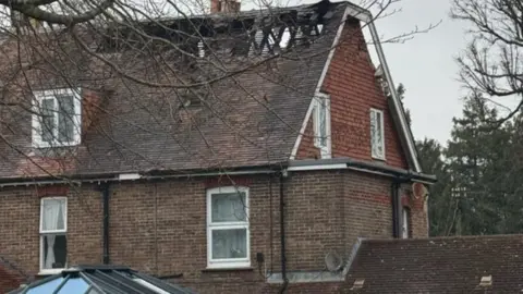 Lisa Hansford Large brick building in daylight - the roof has been beadly damaged by fire