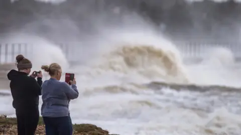 Tim Reekie Two women take pictures of a storm sea