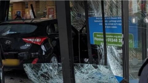 Car smashed through front entrance of hospital, with broken glass surrounding