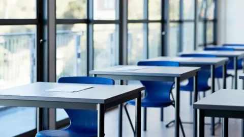 Papers on desks by window in a classroom at a university.
